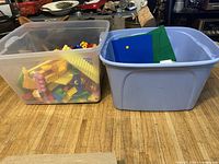 Two bins side by side on floor, one translucent, one blue, showing mixed bricks