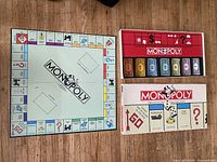 Open Monopoly board next to box lid showing brand and components overview