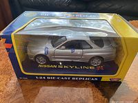 Front angled view of boxed 1:24 silver Nissan Skyline GT-R R34 model