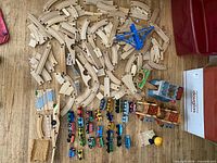 Wide view of all wooden track pieces, train cars and accessories spread on floor