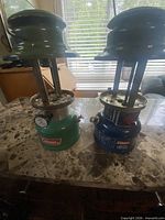 Front view of both Coleman lanterns showing colors and missing globes