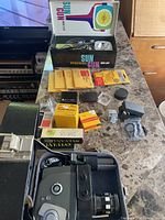 Overall lot view with camera in case, Sun Gun box, Kodak film, accessories