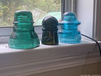 Front view of three differently colored glass insulators on windowsill
