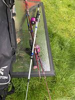 Three kids fishing rods with reels and Easton bag on glass table