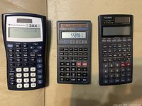 Front view of three calculators showing key layouts and two powered displays
