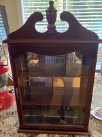 Front view of wood and glass curio cabinet showing overall structure and compartments