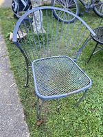 Front view of wrought iron chair showing fan-back and mesh seat