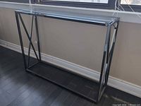 Front view of black metal console table with tempered glass top