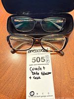 Two eyeglass frames and paper tag inside and outside Coach case