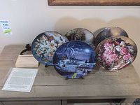 Five porcelain collector plates on display stands