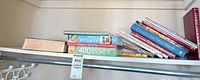 Shelf with entire lot of cookbooks showing horizontal and leaning stacks