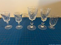 front view of five crystal glasses illustrating varying patterns and heights