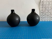 Front view of both black crystal vases on mat with ruler backdrop