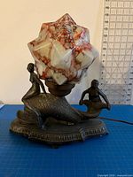 Full view of lamp showing mermaid figures, dolphin base, and starburst glass shade