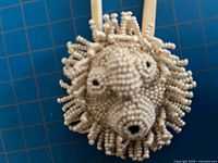 Front view of white beaded mask pendant