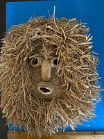 Front view of woven corn husk mask with ruler for scale