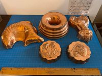 Group shot of all five copper-plated jelly moulds with ruler for scale