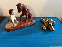 Front view of both chalkware figures on blue grid mat showing overall form and relative size