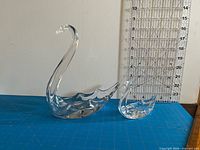 Both glass swans beside ruler for scale