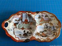 Top view showing full design, scalloped shape, handle, painted scenes, recess