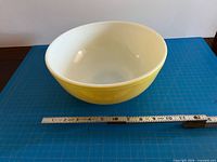 Side view of yellow Pyrex bowl with ruler showing size