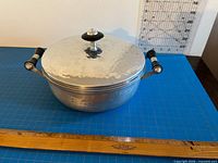 Lidded serving dish side view showing handles, lid and ruler for scale