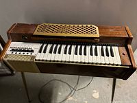 Front view of RCA Pianorgan on brass legs showing keyboard, grille, cabinet