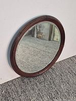 Full view of round wood-framed mirror leaning on wall