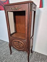 Front view of vitrine showing inlaid panel, missing front glass, ormolu mount