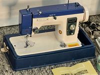 Full view of Janome Vogue Stitch sewing machine with base, foot pedal, manual and accessory case visible