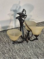 Full view of chandelier showing three amber glass shades and dark bronze frame