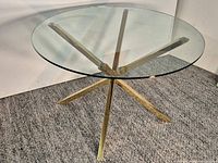 Full view of round glass top and gold X-base table