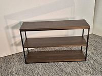 Full frontal view of three-tier console table showing shelves and frame