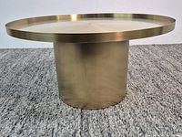 full view of round metal coffee table showing pedestal base and tray top