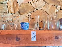 Shelf with assorted clear glass vases and blue and white ceramic planter