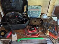 Group view of entire lot on shelf: circular saw in case, saw blades, clamps, respirator, earmuffs, pry bar