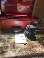 Overview showing toolbox open with tray, pliers inside, sander, manual and box