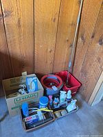 Group view: cardboard boxes, Bissell vacuum box, spin mop bucket, cleaning product baskets