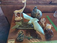 Group view of figurines, stone sculpture, eggs, stone plaque and keychain