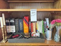 Full shelf view showing books, candlesticks, tray with accessories, pewter stein with pens and flowers