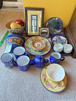 Overview of mixed ceramic tableware, Talavera plates, blue drinkware set, fused glass plate, framed print, bowl with fruit