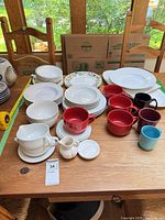 Assortment of plates, bowls, mugs, creamer, sugar bowl and saucers displayed on table