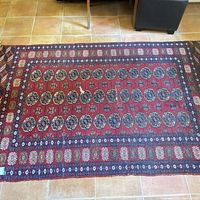 Full view of red Bokhara rug on tiled floor