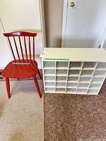 Full view of red chair beside white cubby shelf