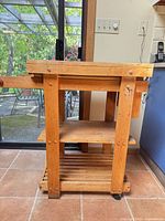 Full side view of wooden kitchen island cart showing shelves and casters