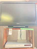 Front view Sony TV on stand with Malata DVD player and remote