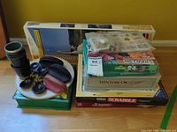 Overall lot showing stacked board game boxes, badminton set, accessories on plate