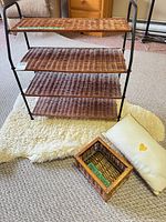 front view of four-tier shelf on rug with basket and pillow