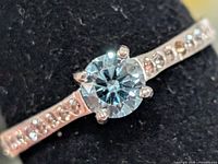 Close-up of ring showing blue centre stone and CZ accents