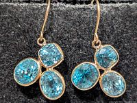 Front view of both earrings showing four-stone blue zircon clusters in yellow gold settings